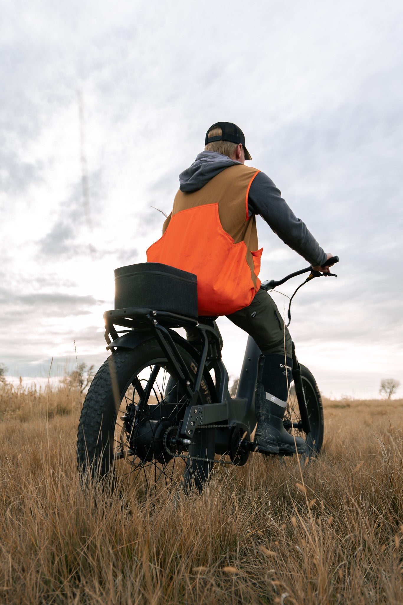 Person riding an eBike in a Field wearing an orange hunting vest