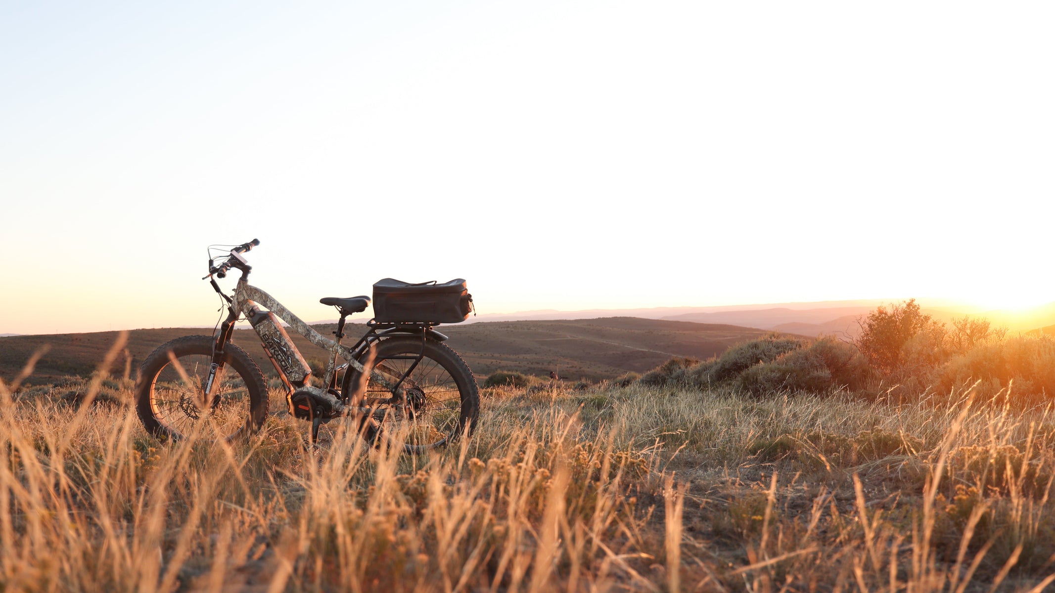 Bicycle with a basket in a field at sunset