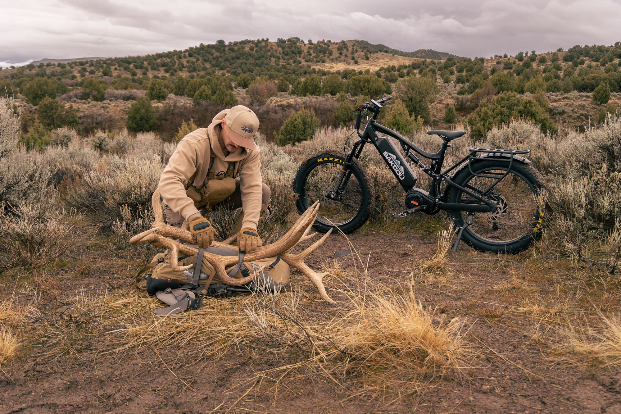 Martin Chag with a Bakcou Storm e-bike in a desert landscape, interacting with a deer antler.