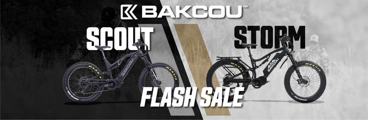A promotional banner for BAKCOU mountain bikes featuring two models: the Scout on the left in a dark black-and-gray setting and the Storm on the right in a light gray setting. Both bikes are black with yellow accents.